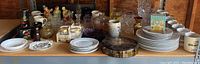 Wide shot of assorted glassware, china, mugs, serving dishes, and figurines arranged on wooden shelves.