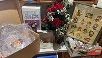 Photo showing boxed vintage glass Christmas ornaments, fiber optic poinsettia box, a green and red floral holiday decoration, and clear plastic serving dishes in a box.