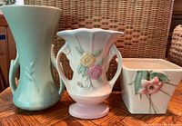 Front view of three Hull Pottery pieces: turquoise vase, floral white vase, and square planter with flower accent.