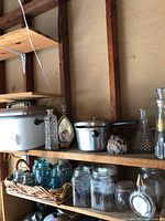 Wooden shelves displaying vintage items: enamel toaster, pressure cooker, various glass jars and insulators.