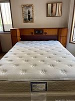 Queen mattress set on wooden headboard with integrated radio and clock and side cabinets