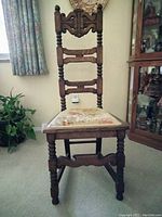 Front view of antique Jacobean mahogany ladder-back prayer chair with carved details and upholstered seat.