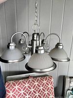 Five-light chandelier hanging, showing frosted ribbed glass shades and brushed nickel finish