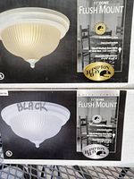 Two boxes of 11-inch dome flush mount lights, one labeled white finish and the other labeled black finish, showing product details and images of the frosted swirl glass shades with solid steel socket housings.