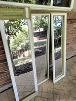 Three white framed full-length mirrors leaning against a wall, showing overall condition and frame design.