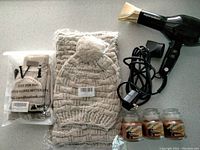 Hair dryer, winter accessories (hat, scarf, gloves), and three pumpkin spice candles arranged on a flat surface