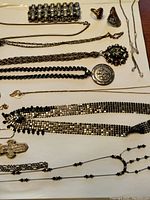 Overhead view of assorted costume jewelry laid out flat on a surface including bracelets, rings, and multiple necklaces with pendants.