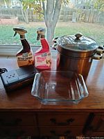 Photo showing the Pyrex 8x8 glass baking dish, two spray cleaning bottles, black alarm clock case, and stainless steel stackable stock pot with metal lid.