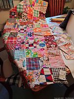 Partially finished patchwork quilt draped on chair showing varied colorful fabric squares