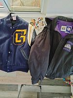 Photo showing the leather letter jacket, Rockies hooded coat, and various medals together on the floor.