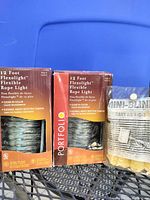 Photo of two Flexolight 12-foot rope lights in brown and orange packaging and mini blind cleaner in its package.