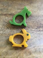 Top view of green dog and yellow rabbit Bakelite napkin holders on wooden surface