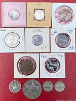 Top view of assorted coins including 1960 US silver dollar, British and international coins in flips and plastic holders