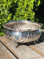 Full view of silver bowl with carved swirl design, scalloped rim, and turquoise stone in floral motif.