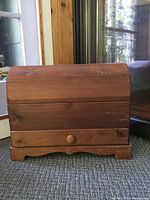 Front view of the antique solid wood farm style trunk showing curved top lid and front drawer with knob.