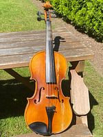 Front view of the antique violin showing the body, fingerboard, and tailpiece with visible surface wear.