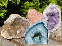Four geodes displayed on wooden surface outdoors