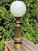 Full view of brass table lamp with globe shade outdoors