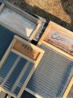 Overhead photo showing three antique wooden wash boards with metal scrubbing surfaces and brand labels visible on two boards