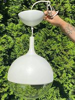 Full fixture held by hand showing canopy, cord and dome pendant