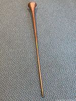 Full length of the copper ceremony horn showing its tapered shape and flared bell.