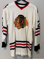 Full front view of white vintage ice hockey sweater with Chicago Blackhawks logo, number 2 on sleeve, and striped ribbed collar, waistband and cuffs.