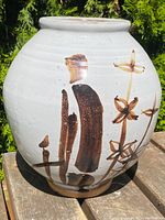 Front view showing spherical shape and brown floral brushwork on white glaze