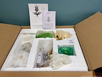 Top view of the chandelier components neatly packed in white foam inside a cardboard box, including crystal parts wrapped in protective paper and gloves.