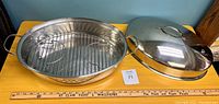 Top-down view of the roasting pan with wire rack inside and lid beside it showing the oval shape and polished stainless steel finish.