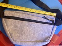 Top view of gray fanny pack showing front with two black zippered compartments and measuring tape.