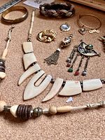 Top view close photo showing multiple pieces of goldtone costume jewelry including necklaces, bracelets, earrings, and pendants.