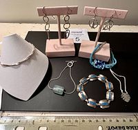Photo showing entire lot including sterling bracelets, dolphin earrings, handcrafted sterling hoop earrings, Murano glass bracelet, and necklaces on display stands.