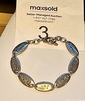 Sterling silver bracelet arranged in a semi-circle with visible engraved words on oval links.