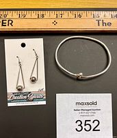 Photo showing the sterling silver dangle earrings displayed on a branded card and the sterling silver open bangle bracelet.