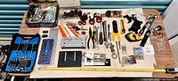 Overview of the assorted tool lot spread out including wrenches, sockets, pliers, screwdrivers, clamps, mounts, and hardware pieces on a table.