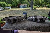 Photo of two automotive headlights from rear side, showing mounting and electrical connection points, with a restoration kit box between them, set outdoors on a stone table.