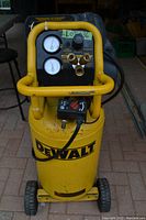 Front view of compressor control panel showing two pressure gauges, regulator knob, and three brass couplers