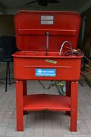 Front view of red King Canada parts washer with lid open, showing sticker label, legs, and shelf.