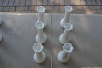 Top-down view showing six white bud vases arranged in two rows, highlighting the scalloped edges of the vase mouths and ribbed body texture.