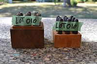 Two sets of number stamp dies mounted in wooden blocks, one darker and one lighter wood, arranged vertically on a stone surface outdoors.