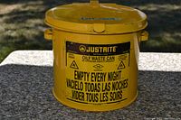 Front view showing yellow oily waste can with printed safety warnings and capacity details