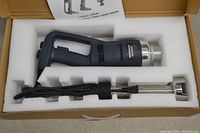 Commercial immersion blender in original box with molded foam padding. Handheld blender body with power cord and removable stainless steel blending shaft. Label on blender reads 'Immersion Blender'.