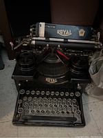 Front and top view of black Royal typewriter with glass round keys and metal framing.