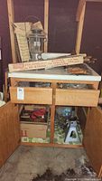 Full view of cabinet with hand saws, jack stands, lantern, and folding hi-stand box on top