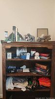 Front view of wooden bookcase showing books, gloves, hats, baseball, and figurines