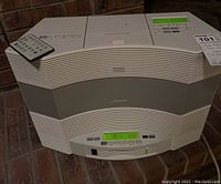 Front angle view of Bose music system showing unit with digital display on, remote control on top
