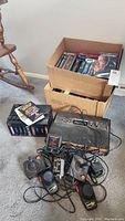 Overview of lot showing Atari 2600 console, multiple controllers, game cartridges, and VHS boxes