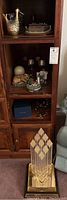 Full shelving unit showing multiple collectibles including a large clear abstract sculpture at bottom.