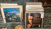 Stack of vintage LP records featuring Ella Fitzgerald and The Best of Peter Gunn as the first visible albums on top.