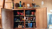 Wooden cabinet open showing multiple small plant pots and various gardening supplies inside.